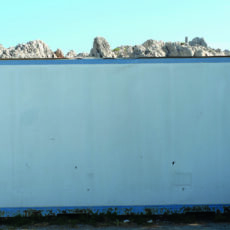 Eine Weiße Wand, mit Felsengebirge in der Ferne.