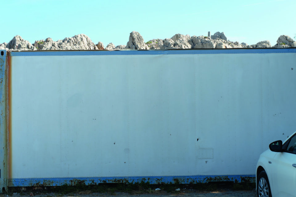 Eine Weiße Wand, mit Felsengebirge in der Ferne.