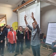 Roman Huber, Vorstand des Vereins „Mehr Demokratie e. V" Hebt seine Arme in die Runde. Um den 4 minütigen Demokratie Diskussionsformat zu erklären.