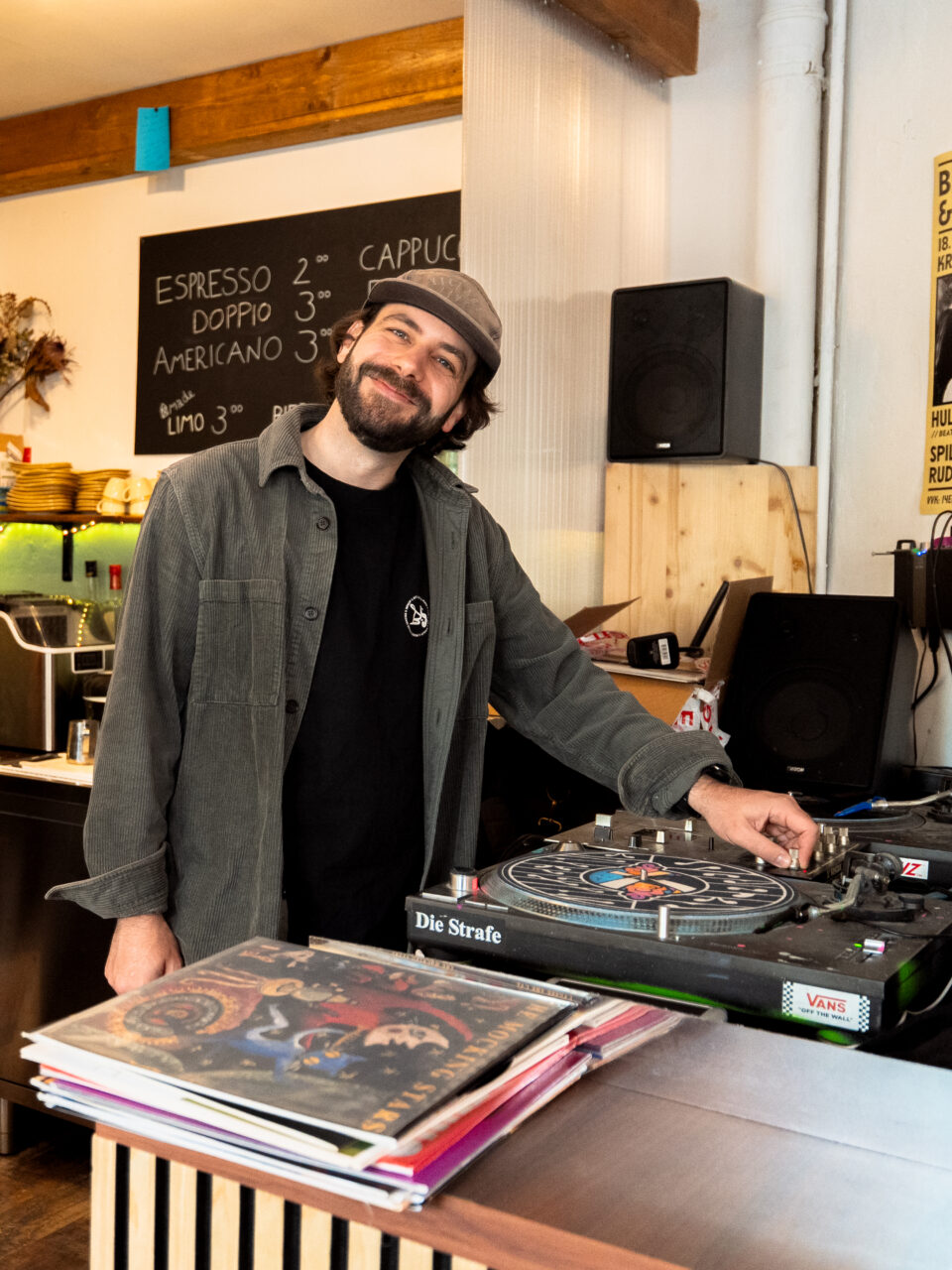 Patrick grinst vor den Turntables in seinem Wiesabadener Cafe